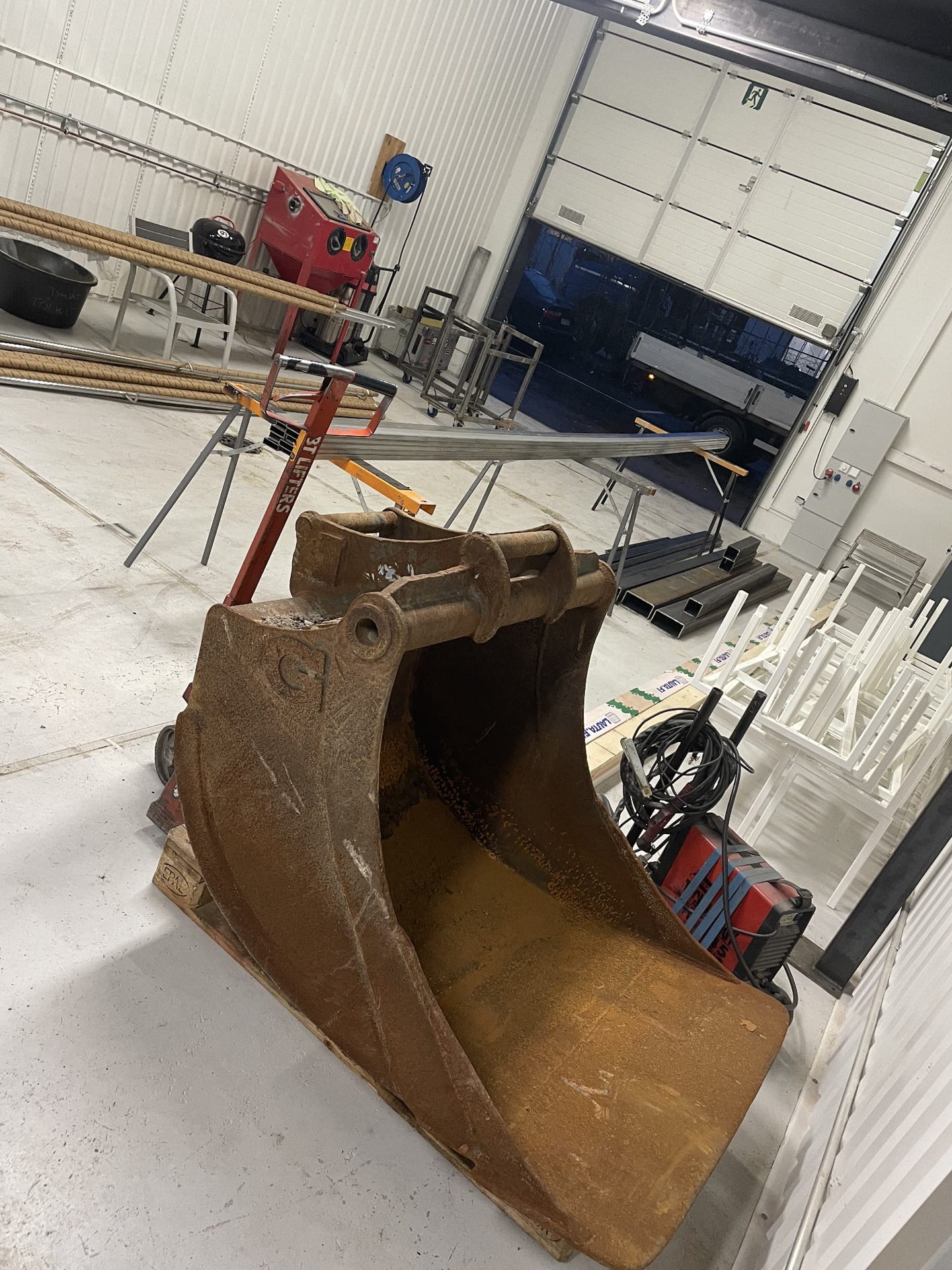 An excavator bucket undergoing repair at the workshop.