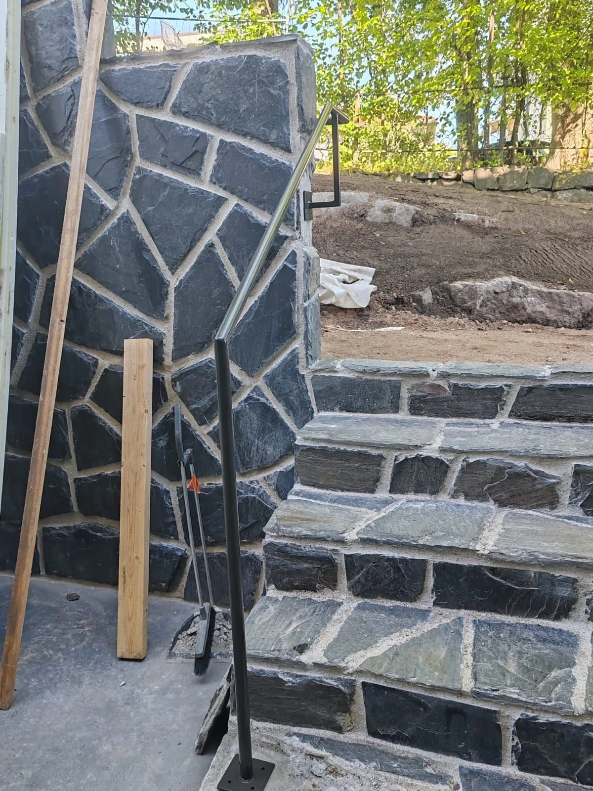 A handrail fixed to the stone facade beside the stairs.