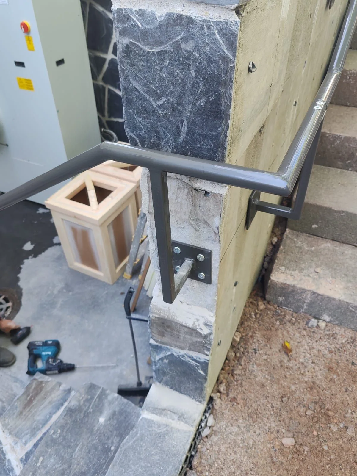 A black handrail corner and its fixing to a concrete wall.