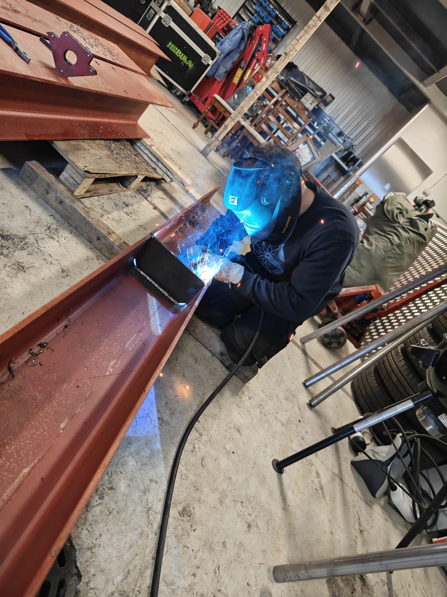 A welder working on a steel beam joint.