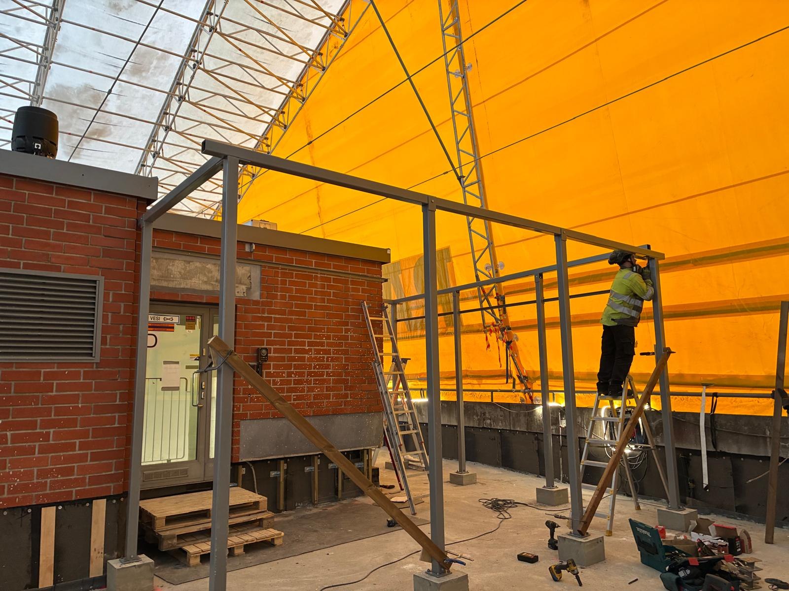 A worker installing a steel frame on a protected construction site.