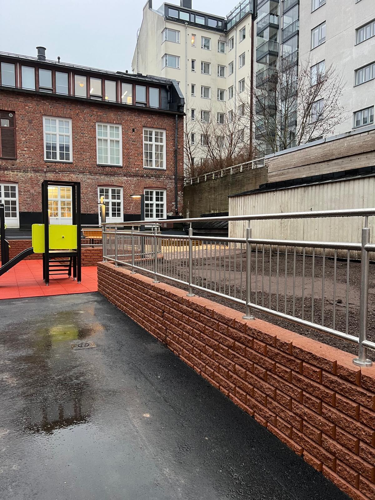 Completed metal railings on a brick wall in a courtyard between buildings.