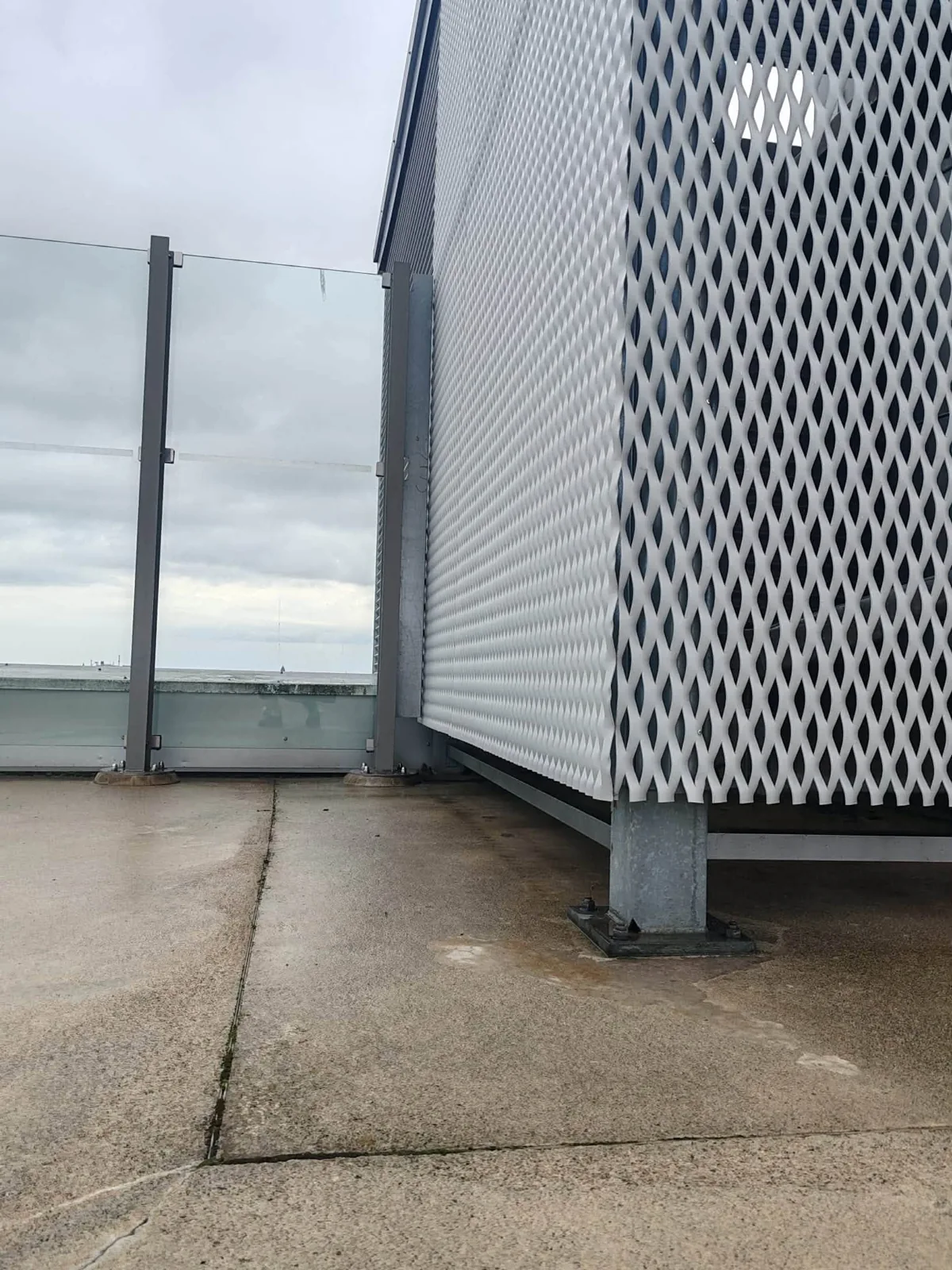 A mesh-clad structure beside the glass railing.