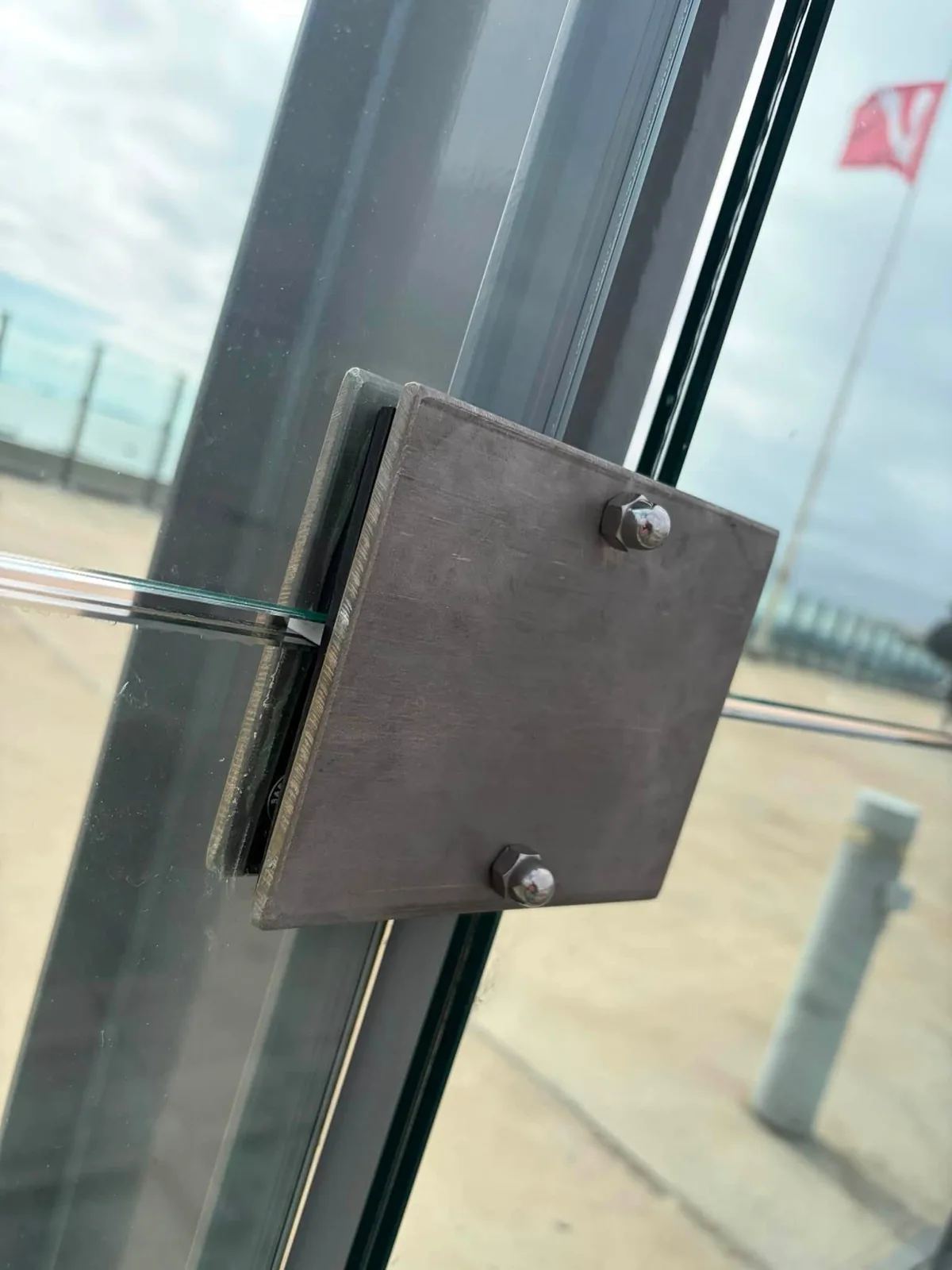 Detail of a metal fixing on a glass railing.