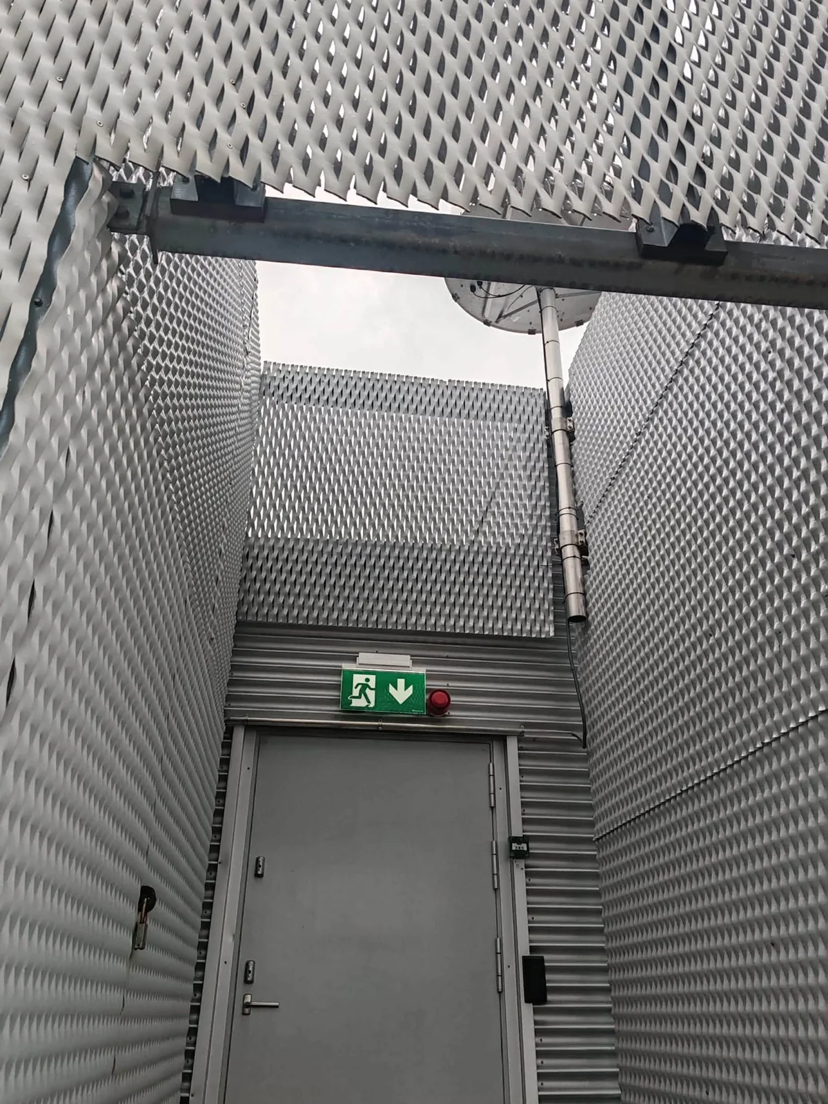 A passage to an exit door enclosed by mesh structures.