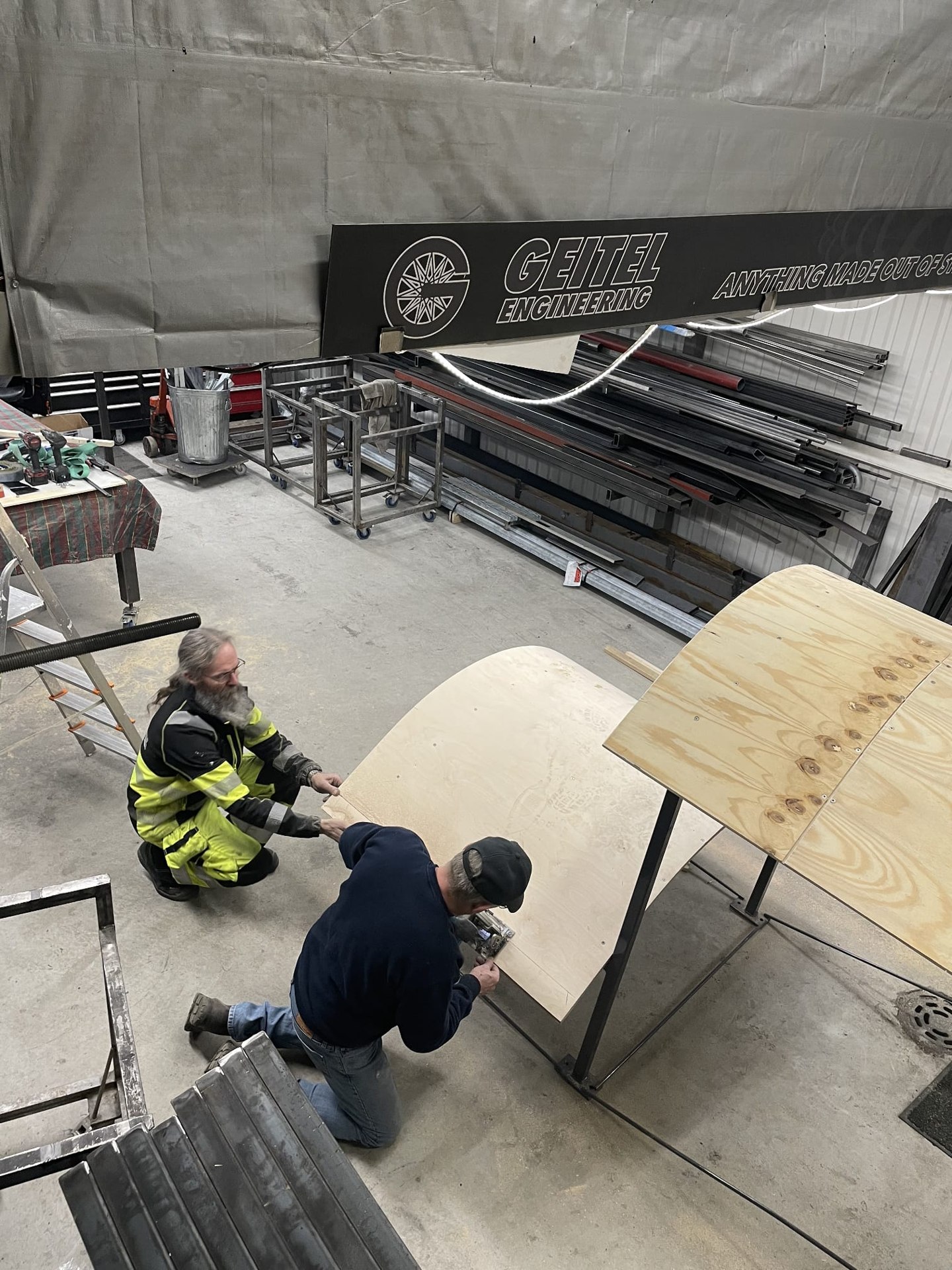 Workers fitting a curved component at the Geitel Engineering workshop.